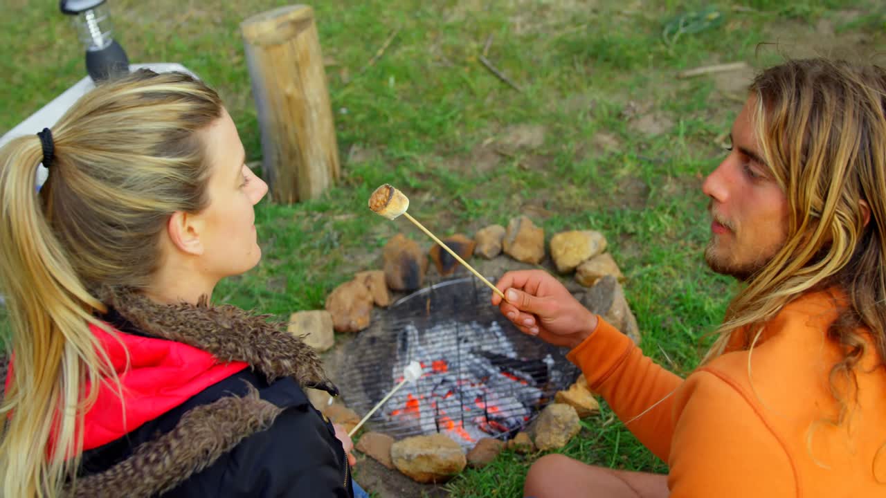 молодой человек кормит женщину зефиром возле костра 4к