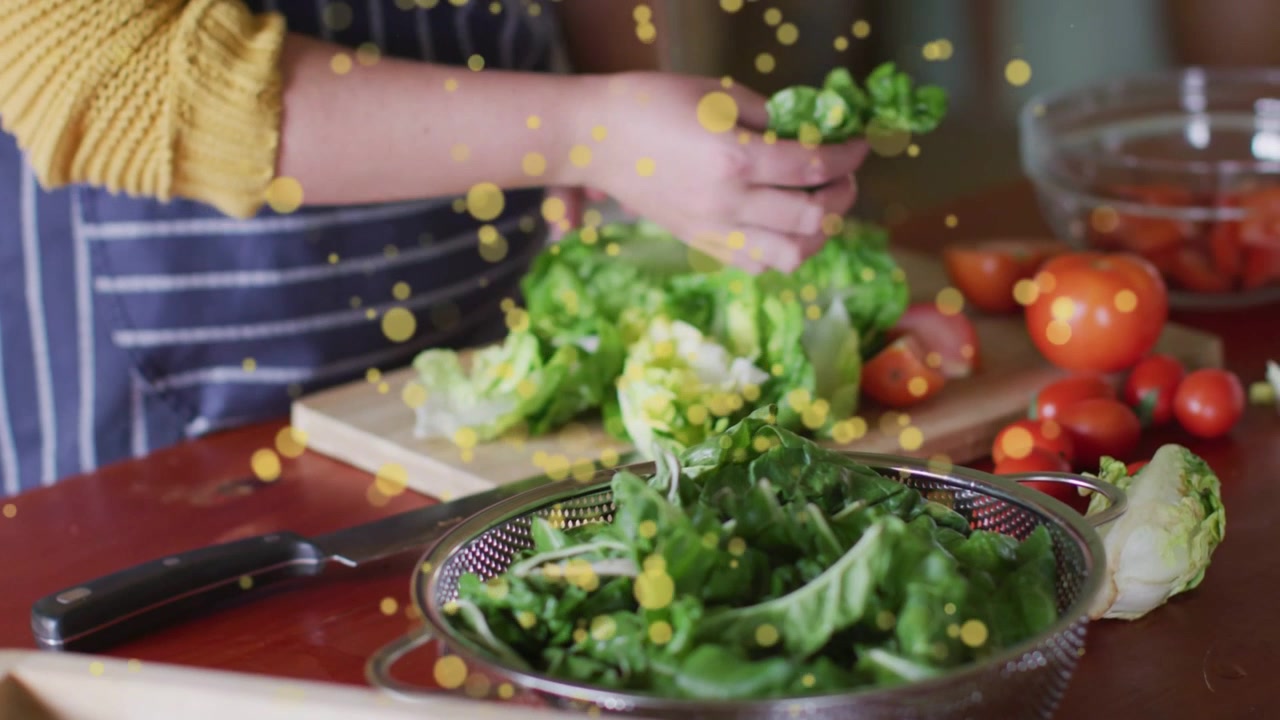 Cuoco che prende la lattuga, strappando le foglie in una ciotola per la preparazione dell'insalata, con un overlay giallo sulle mani.