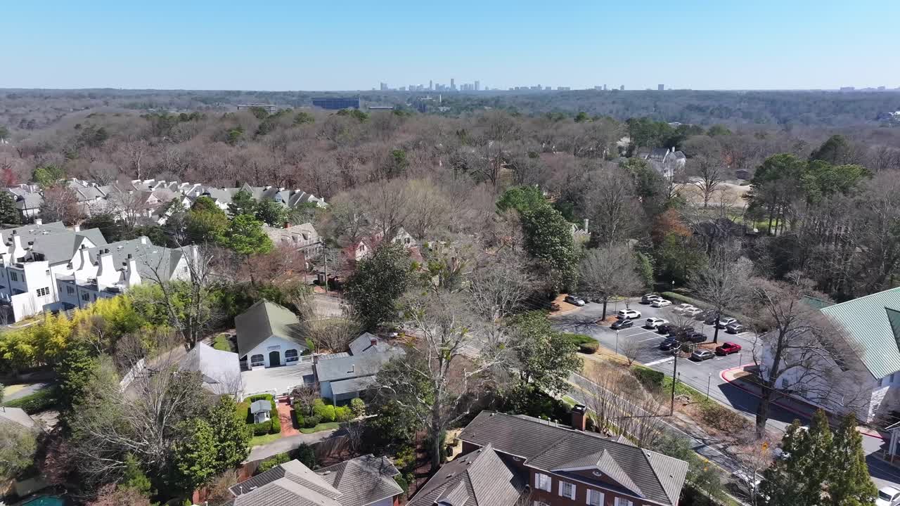 Vinings village condominium complex buildings and neighbourhood surrounded by trees, parks with downtown Atlanta skyscrapers at far, Georgia, Aerial