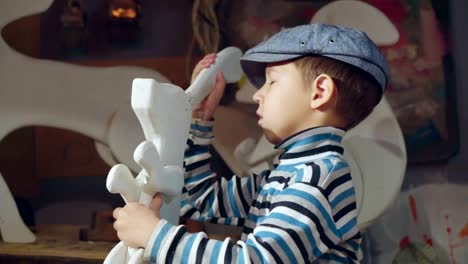 cute boy is repairing toy bunny in home workshop