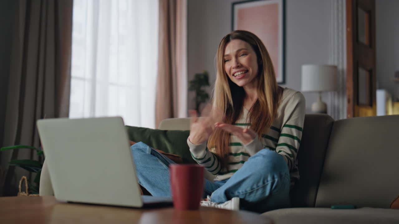 Lady smiling video conference laptop sitting home couch. Excited woman videocall