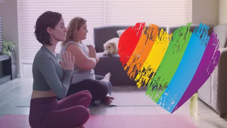 Animation-Eines-Regenbogenherzens-über-Einem-Kaukasischen-Lesbischen-Paar,-Das-Zu-Hause-Yoga-Praktiziert