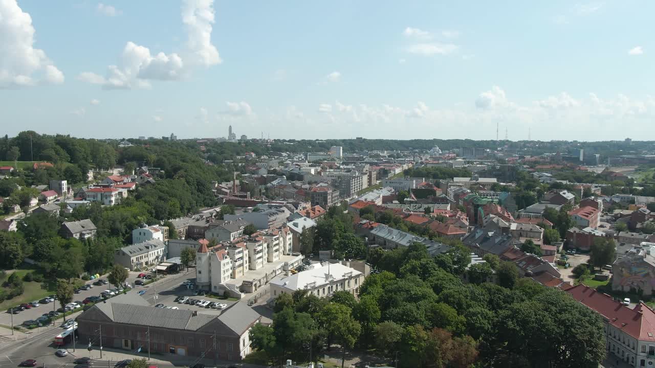 Aerial drone view slowly descending while showing beautiful city of Kaunas with bright blue sky and trees in Lithuania