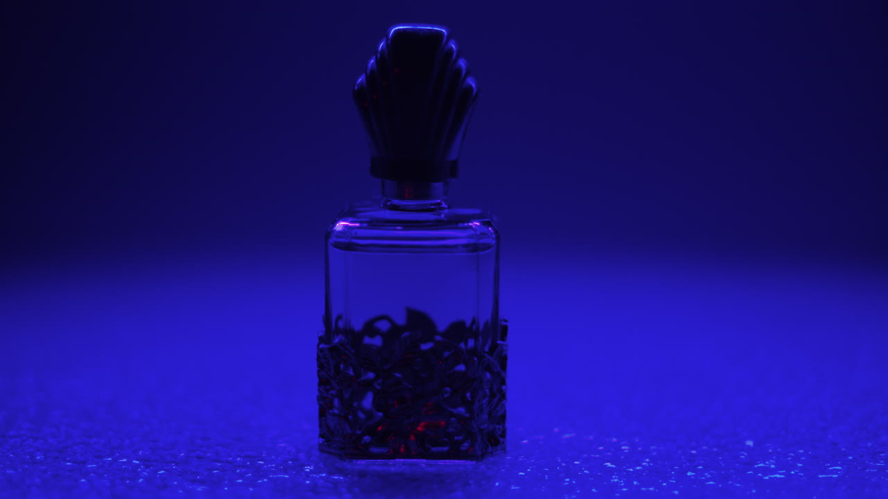 video del producto de una botella de perfume vintage, aislada en un fondo atmosférico azul oscuro