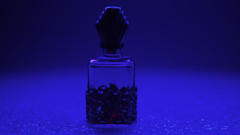 Product-video-of-a-vintage-perfume-bottle,-isolated-in-a-dark-blue-atmospheric-background
