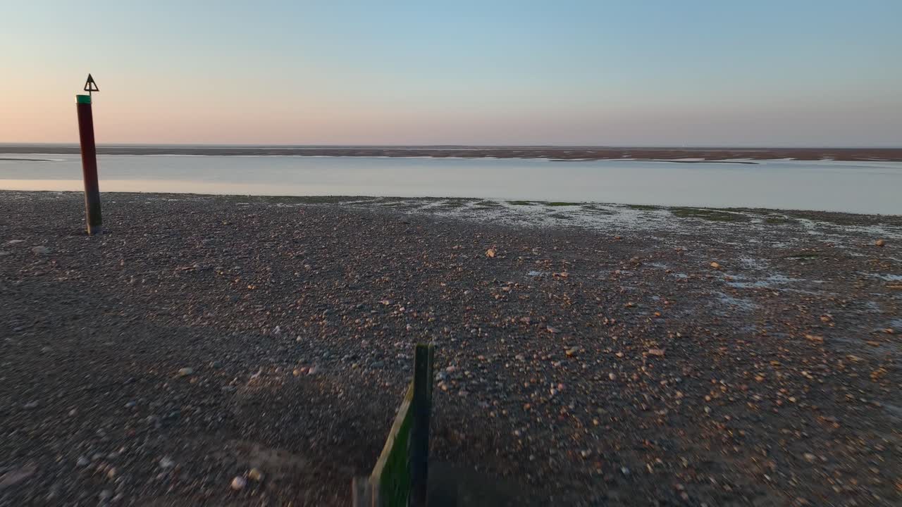 Flight over concrete jetty and out over incoming tidal channel at sunset. Fleetwood, Lancashire, UK.