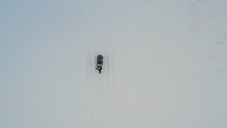 vista aérea de arriba hacia abajo de la madre empujando el cochecito del bebé en un campo de campo nevado