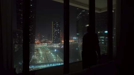silhouette of a man at night in a big city going out on the apartment balcony