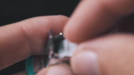 man opens small stapler to put in clips on dark background