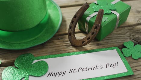 happy st patricks day text with shamrocks and green hat with copy space on wooden table