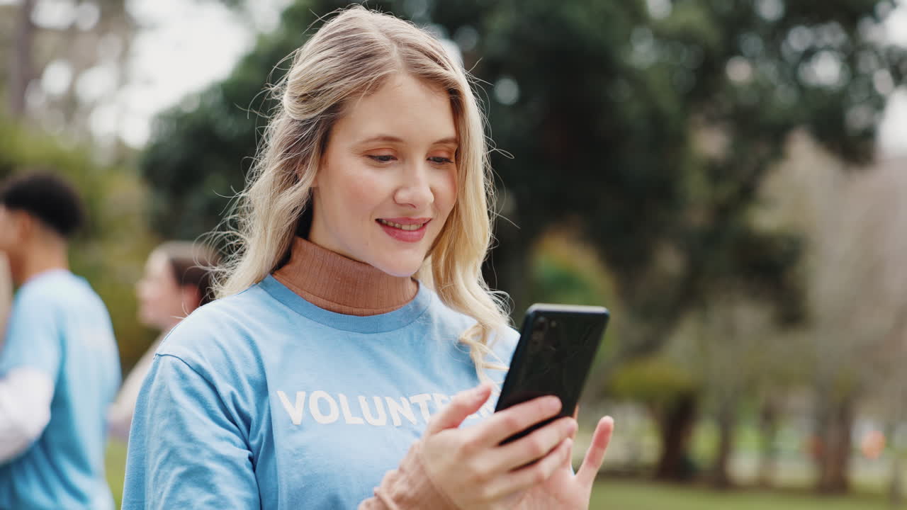 mujer voluntaria en un parque, sonriendo y mirando su teléfono