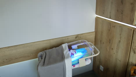 transparent baby crib with a child in it lying on uv lamp. infant is treated from hyperbilirubinemia in maternity hospital.