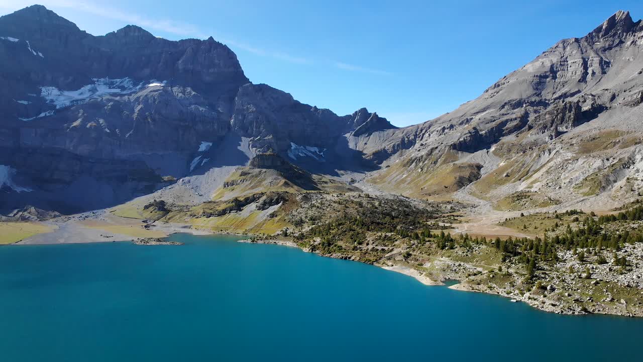 Aerial flyover over the hydrolectric dam and Lac de Salanfe in Valais, Switzerland on a sunny autumn day in the Swiss Alps with a view of alpine peaks and cliffs in background