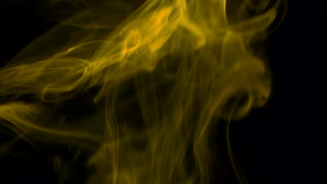 clouds of yellow smoke slowly rising graceful twists upward. colored smoke blowing from bottom to top. close-up, isolated on black background