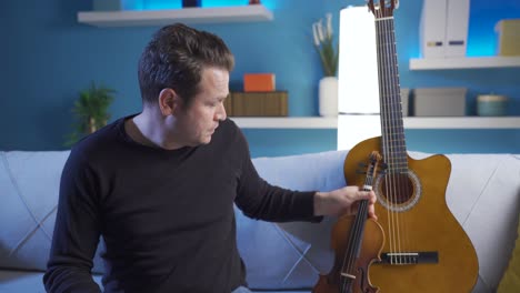 hombre triste tocando la guitarra acústica en casa.