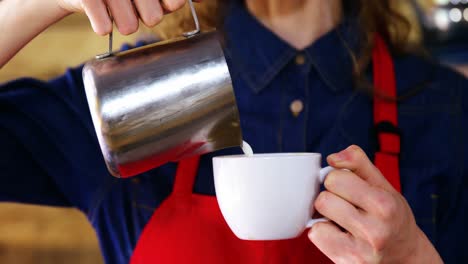 Waitress-pouring-milk-in-coffee-at-counter