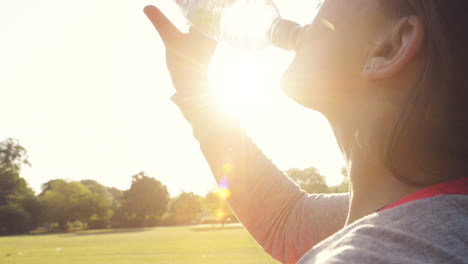 fitness woman drinking water outdoors in park