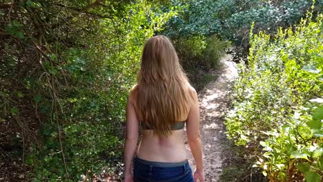 a woman walking through a forest by the ocean with beautiful views in slow motion