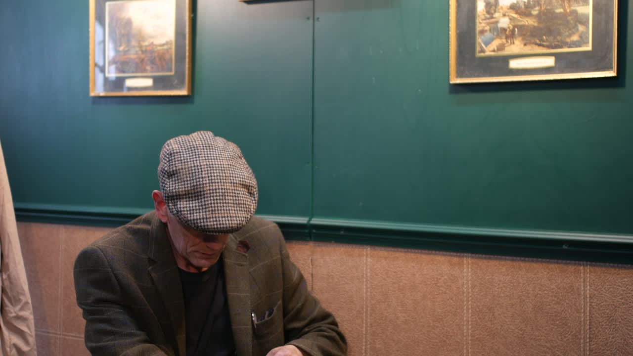 Older Man Reading and Drinking in a Pub