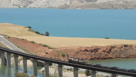 diesel cargo train crossing a bridge beside the idriss first dam