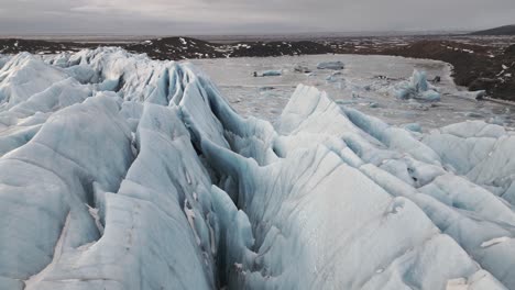 dramatic crevasses of vatnajokull glacier in iceland, low aerial dolly in on overcast day