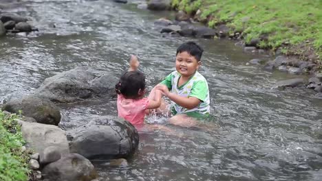 two asian children playing water in the river in a mountainous area