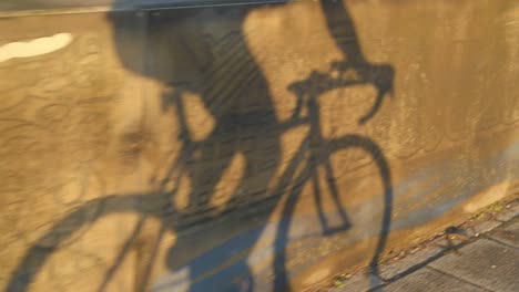 slow motion tilt shot shadow of cyclist riding bike to commute to work during sunrise sunset