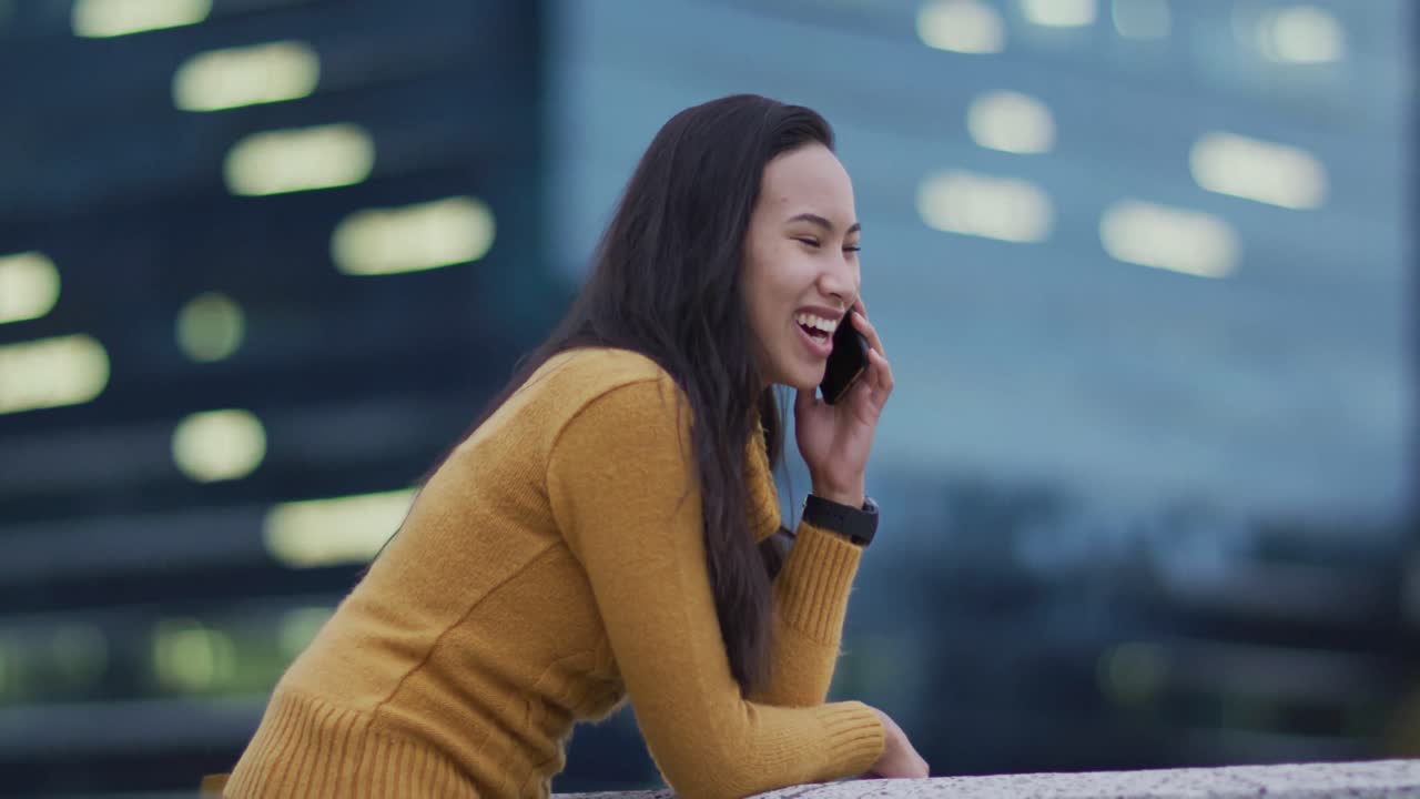 스마트폰으로 얘기하고 미소 짓는 아시아 여성
