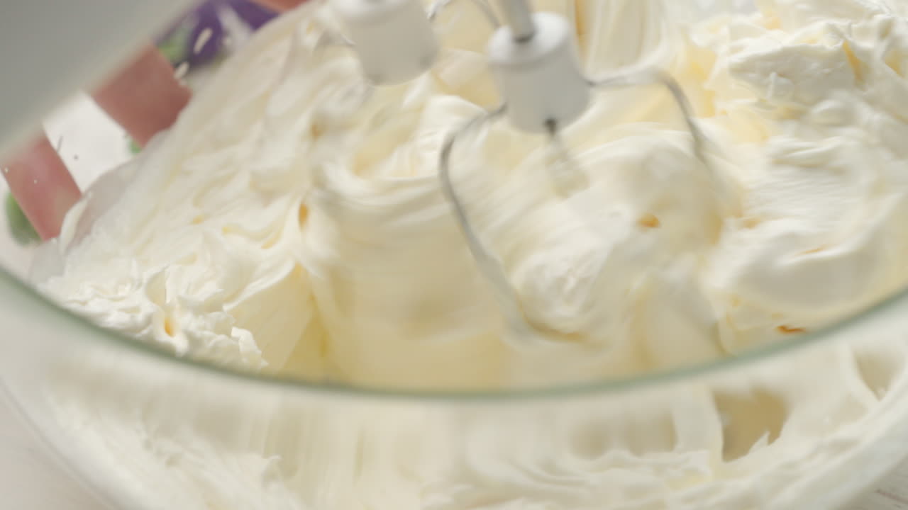 Close-up de chantilly sendo misturado com queijo mascarpone, mergulhando twisters no creme.