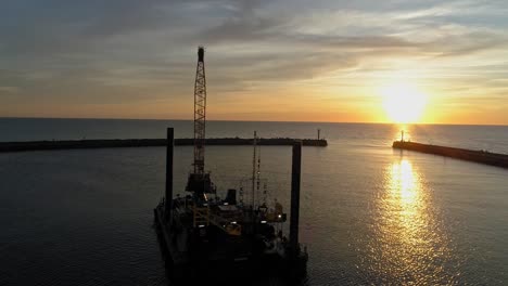 silhouette of hydraulic equipment service with a fiery sunset and reflection at the baltic sea in darlowko, poland