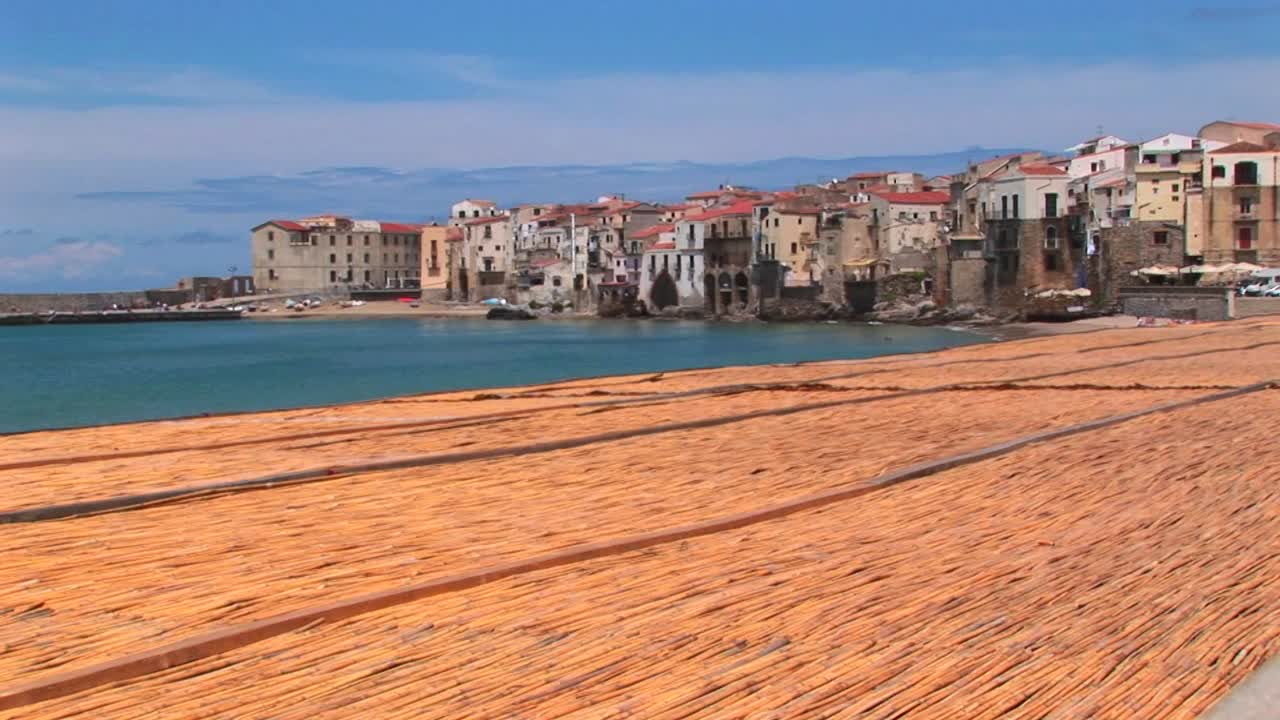 Uma praia limpa e cuidada perto de casas ao longo da costa em Cefalù, Itália.
