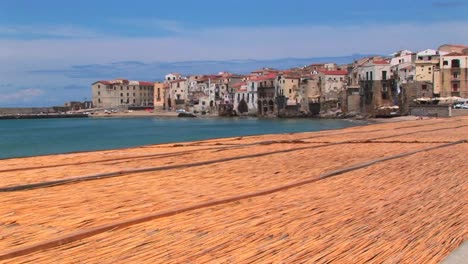 A-combed-beach-near-houses-along-a-shoreline-in-Cefalu-Italy--