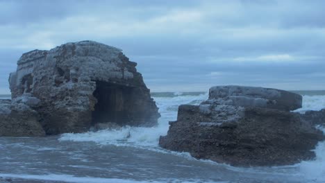 Big-stormy-waves-breaking-against-abandoned-seaside-fortification-building-ruins-at-Karosta-Northern-Forts-in-Liepaja,-wide-shot