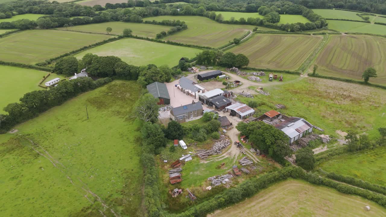 Drone view of a lumber operation within a small freeholding surrounded by fields and trees in a rural area