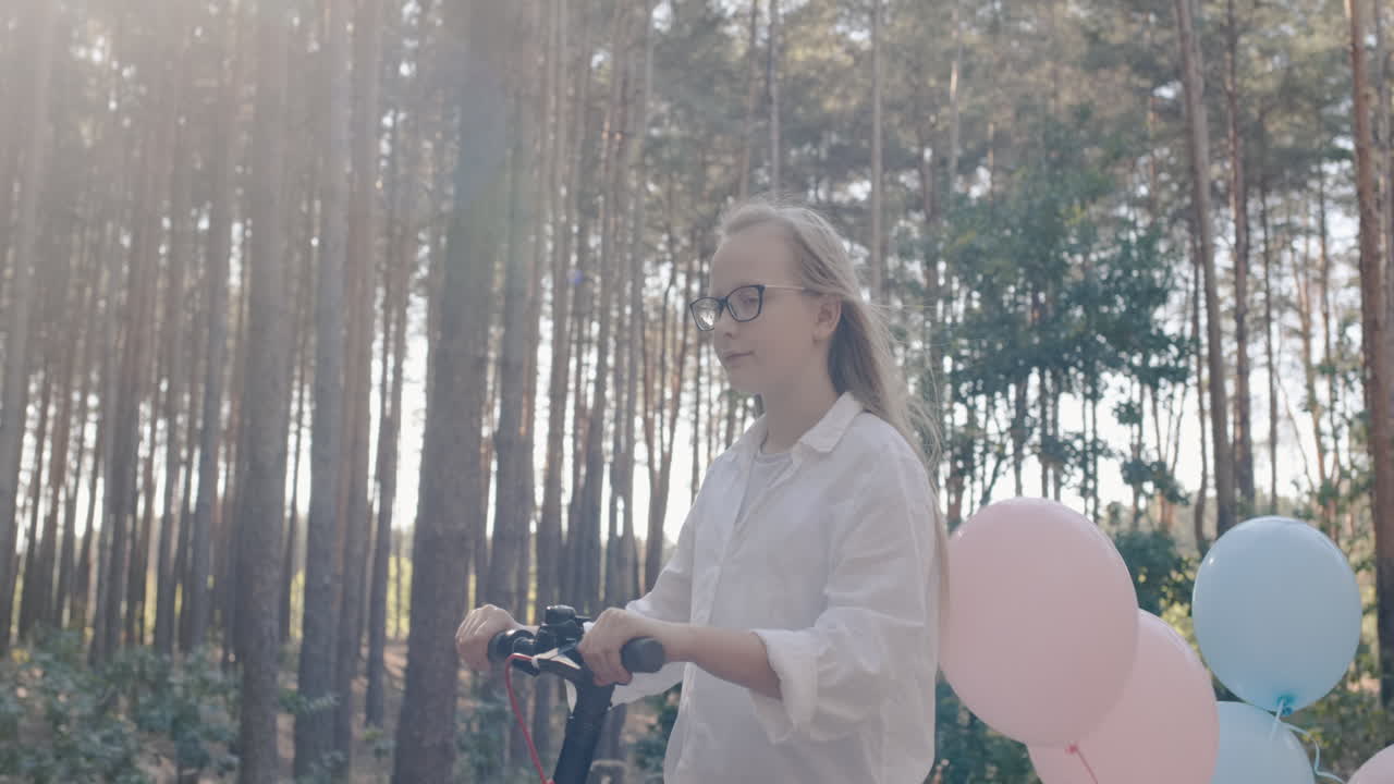 bebé feliz monta en scooter eléctrico con globos atados