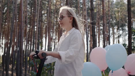 happy baby rides on electric scooter with balloons tied