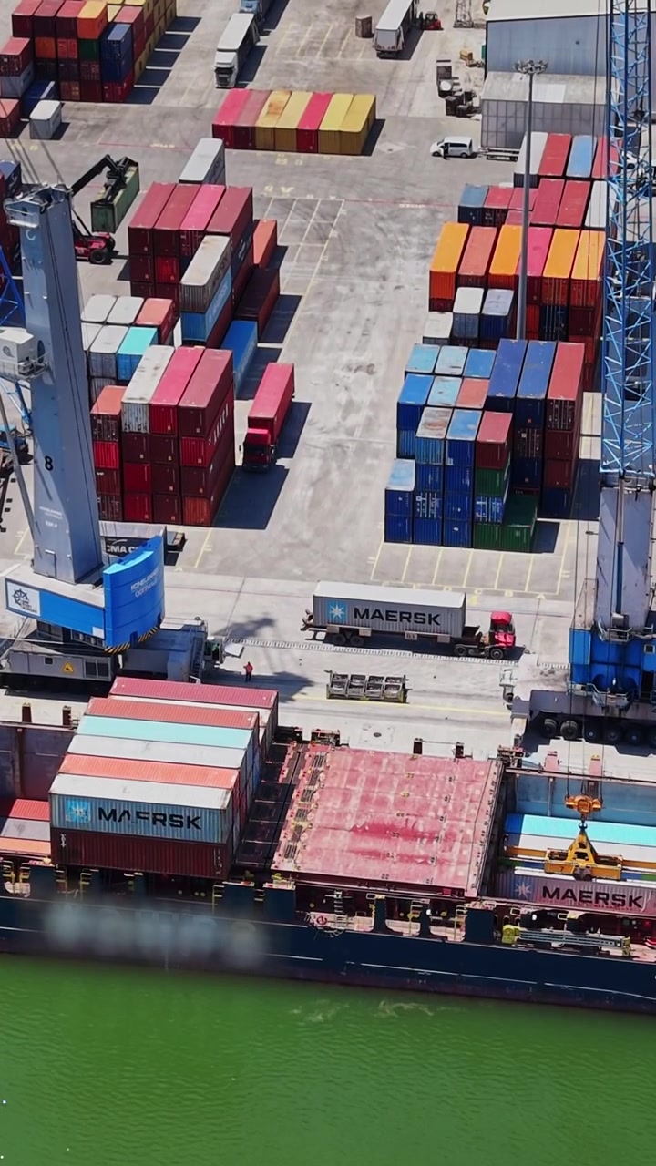 Container ship loading goods at a busy port with stacked containers