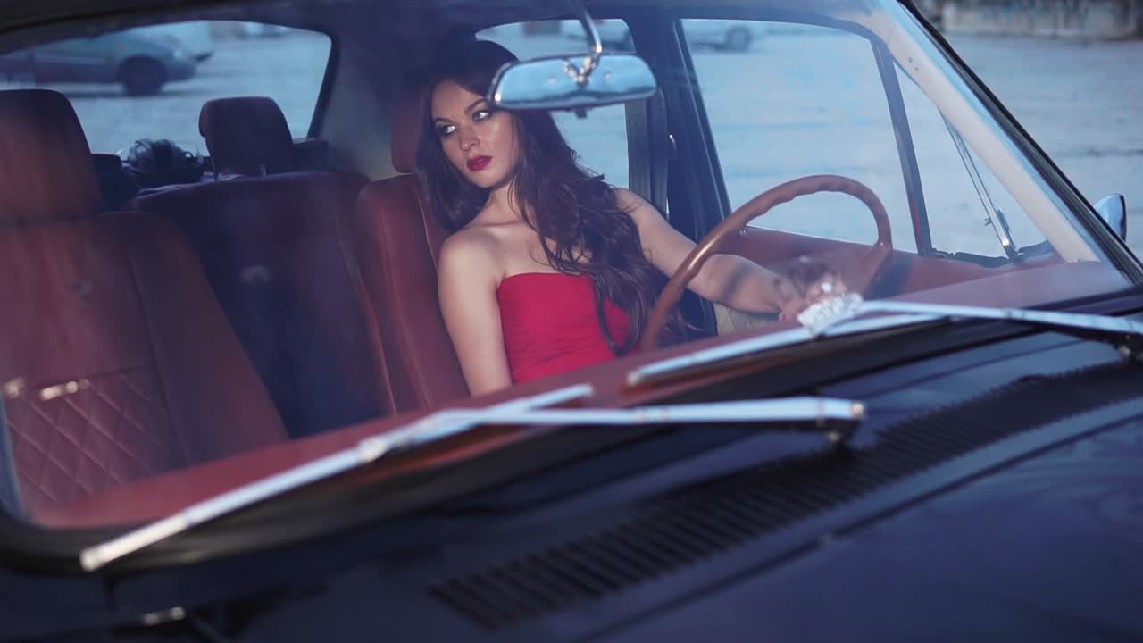 Woman in Red Dress Driving a Vintage Car