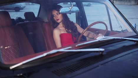woman in red dress driving a vintage car