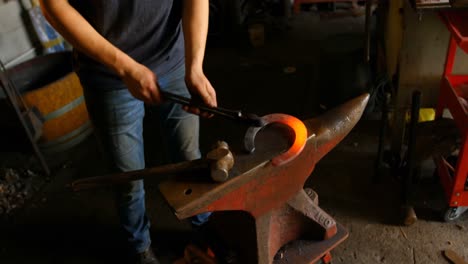 Female-metalsmith-holding-horseshoe-in-factory-4k