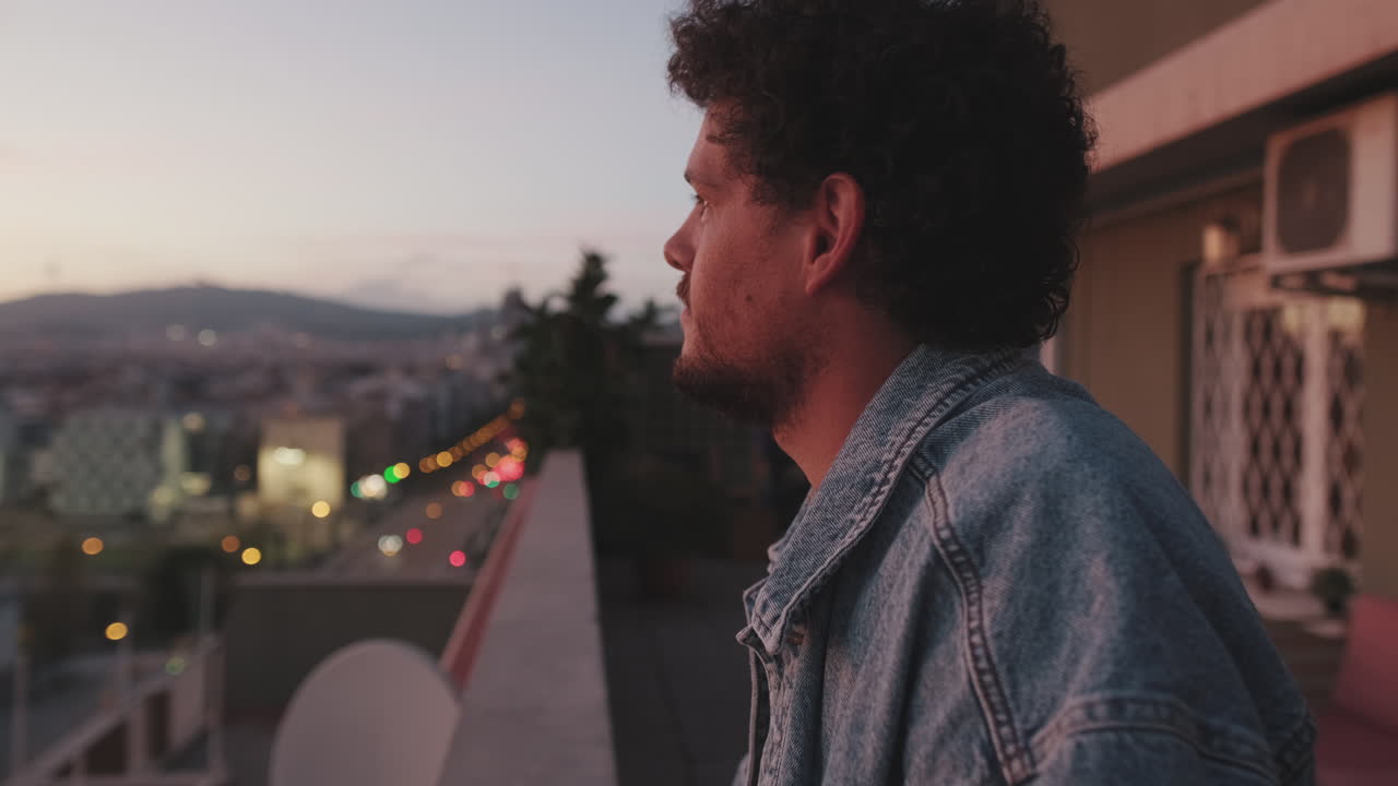 Man on a balcony at sunset overlooking the city