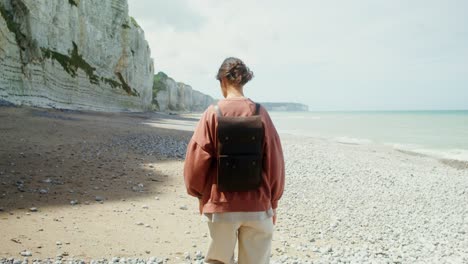 woman hiking on the beach with cliffs