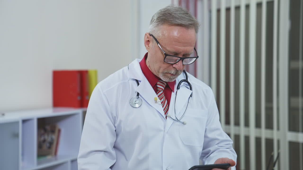Professional doctor using mobile phone for medical consultation. Senior doctor learning to work on a phone in medical center. Remote work during pandemic.