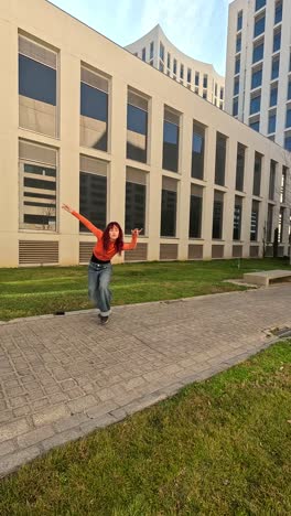 young woman picking up smartphone and dancing in university campus