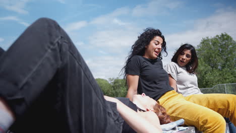 three female friends meeting and relaxing in urban skate park