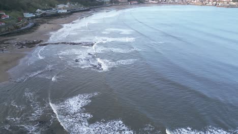 Aerial-drone-top-down-shot-over-beach-along-seaside-in-Scarborough,-North-Yorkshire,-UK-during-evening-time