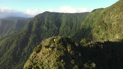 aerial shot with orbit motion of male hiker standing at the end of a cliff on a mountain peak at border ranges national park, new south wales in australia