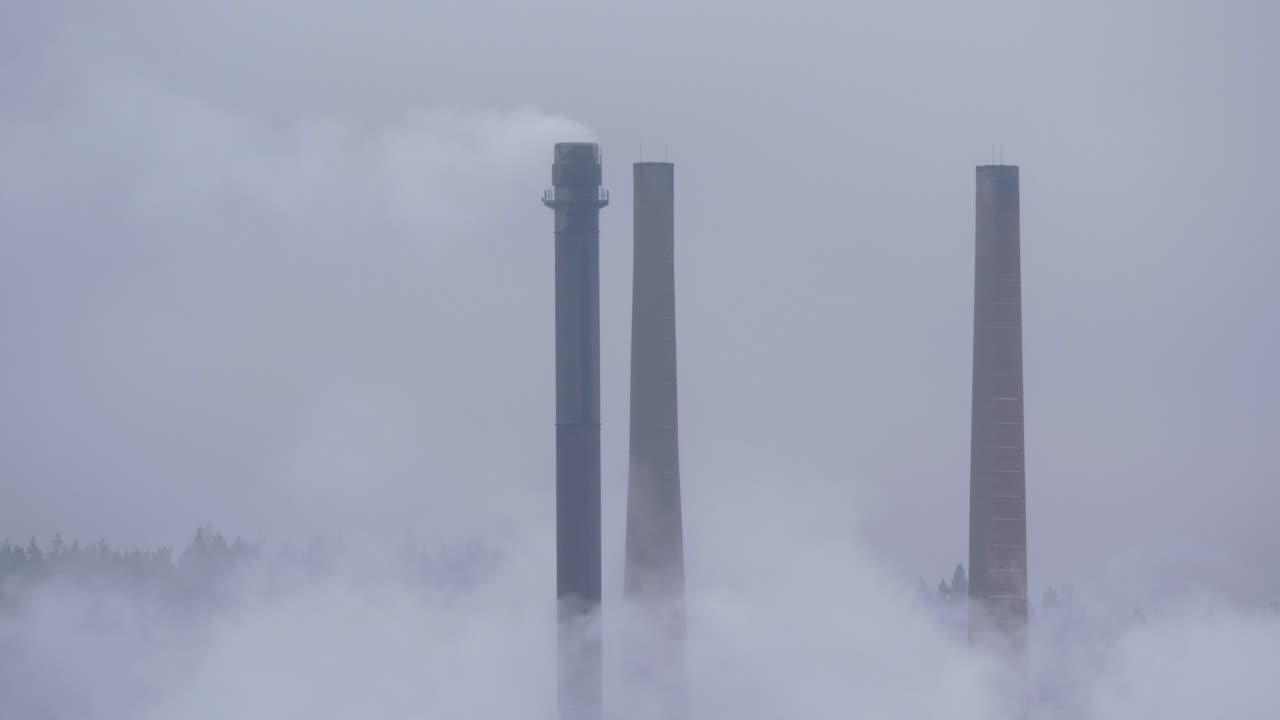 추운 흐린 날에 제지 공장 굴뚝이 굴뚝을 대기로 내뿜고 있습니다.