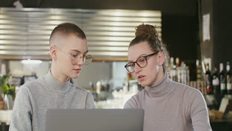 two women collaborating on a laptop in a cafe