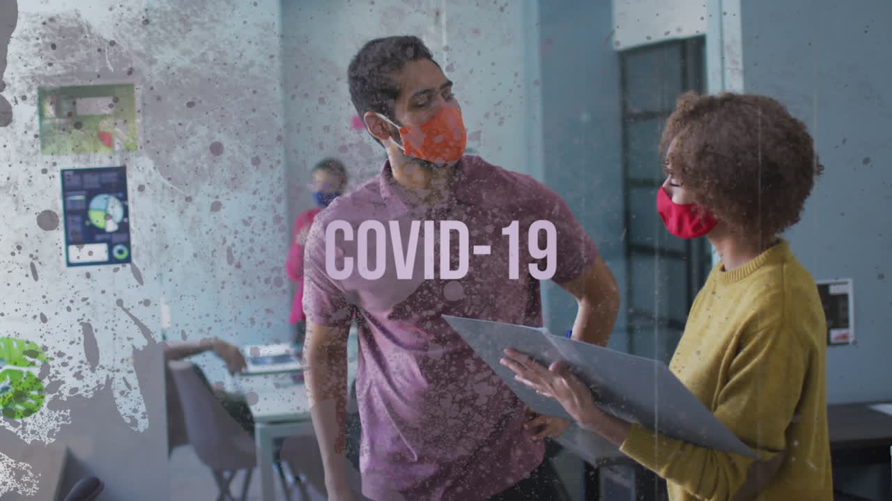 Covid-19 text against male and female office colleague wearing face mask discussing at office